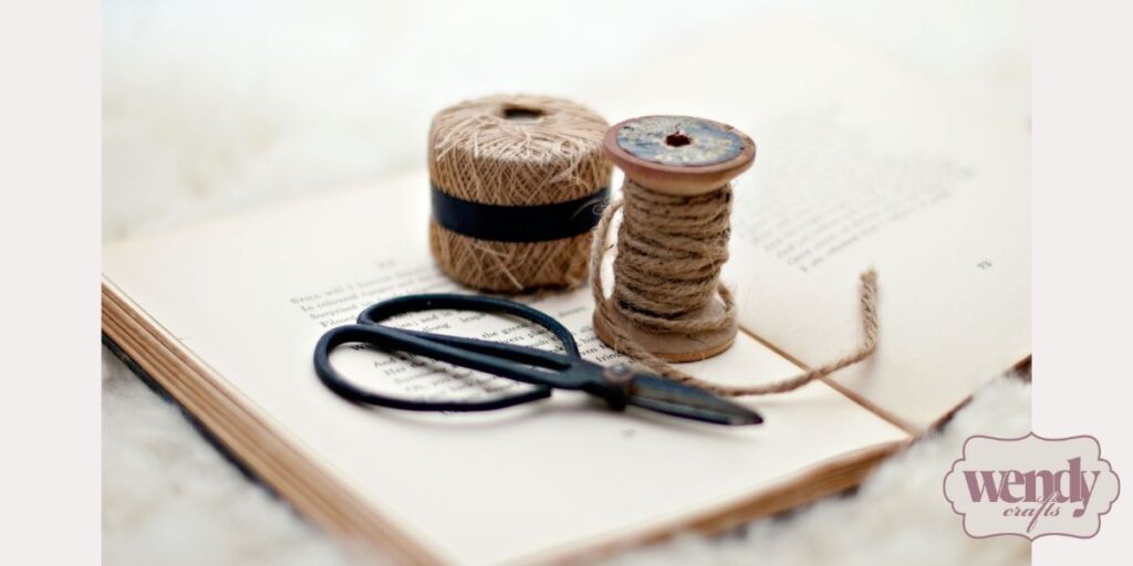 Twine, natural thread, and scissors placed on an open book.