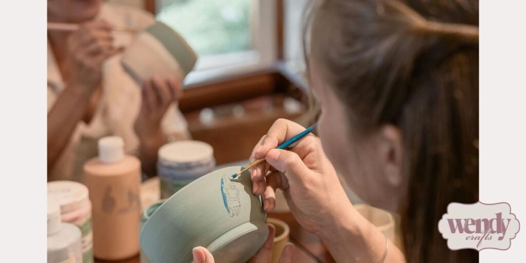 Two women painting designs on pottery.